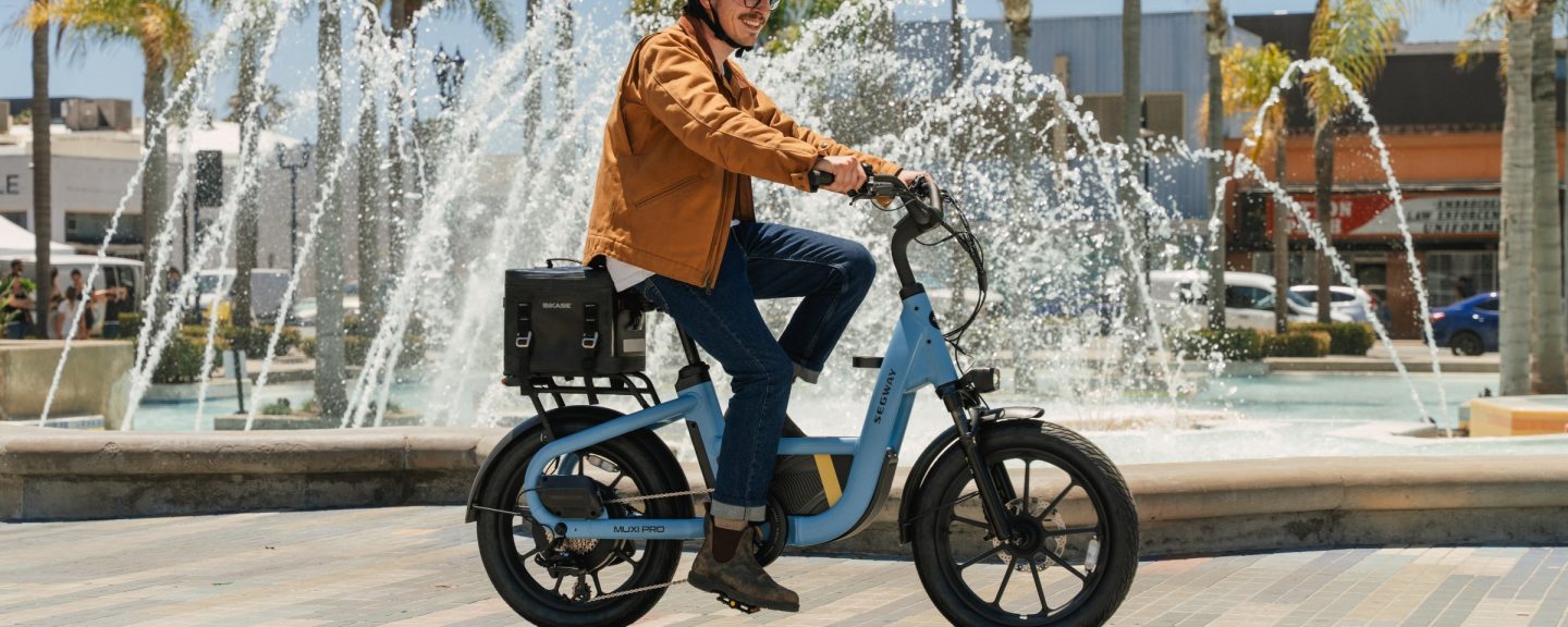 Rider on a Segway MUXI Pro cargo e-bike in a sunny city plaza