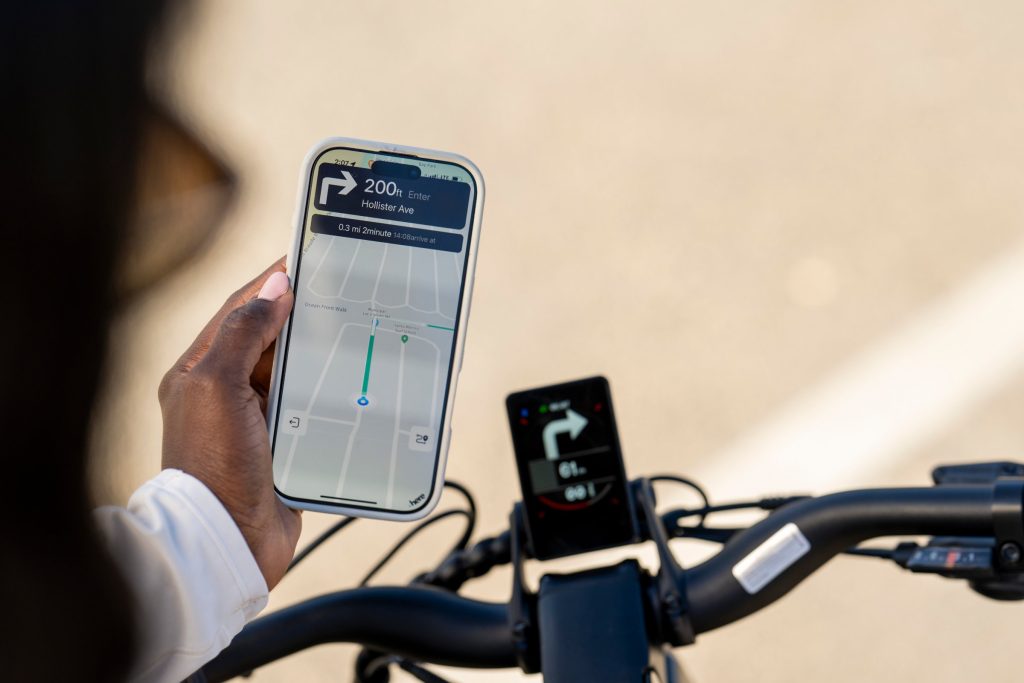 Rider holding a smartphone next to a Segway Xafari eBike