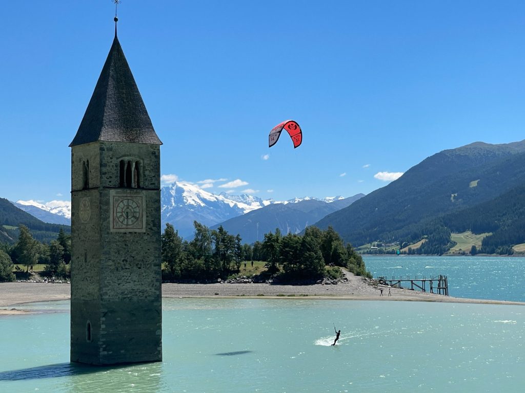The sunken church bell tower rising out of Lake Reschen with mountains behind