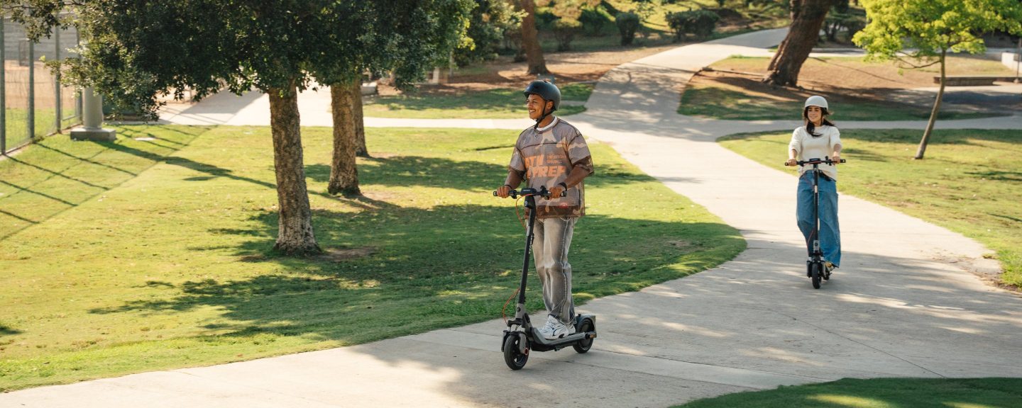 Two riders on Segway E3 Go electric scooters on a curving park path