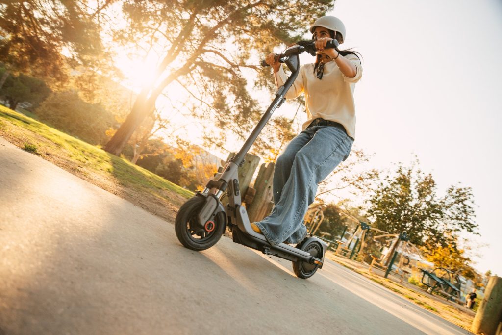 Rider wearing a helmet leaning into a turn on a Segway E3 Go electric scooter