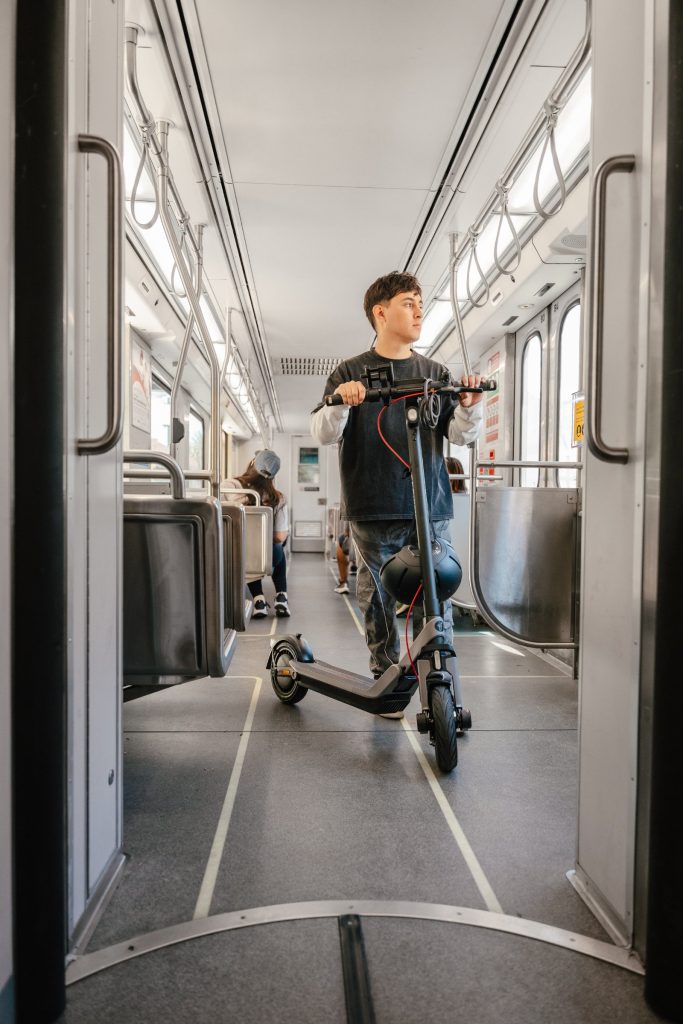 Commuter standing with a Segway E3 Pro electric scooter on a train