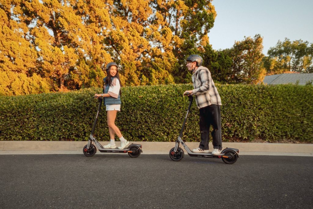 Two riders cruising down a tree-lined street on Segway E3 Pro electric scooters