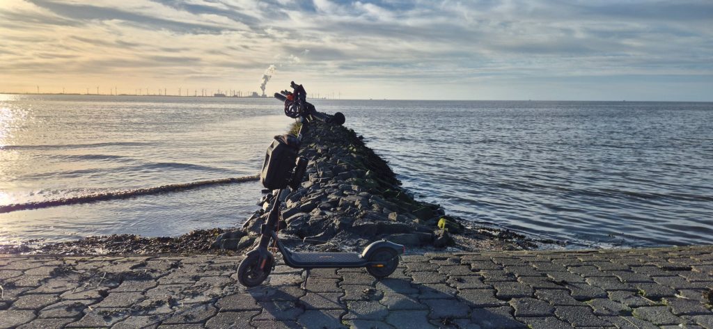 The Segway F2 Pro the rider calls Black Scooter, parked on rocks by the sea at sunset.