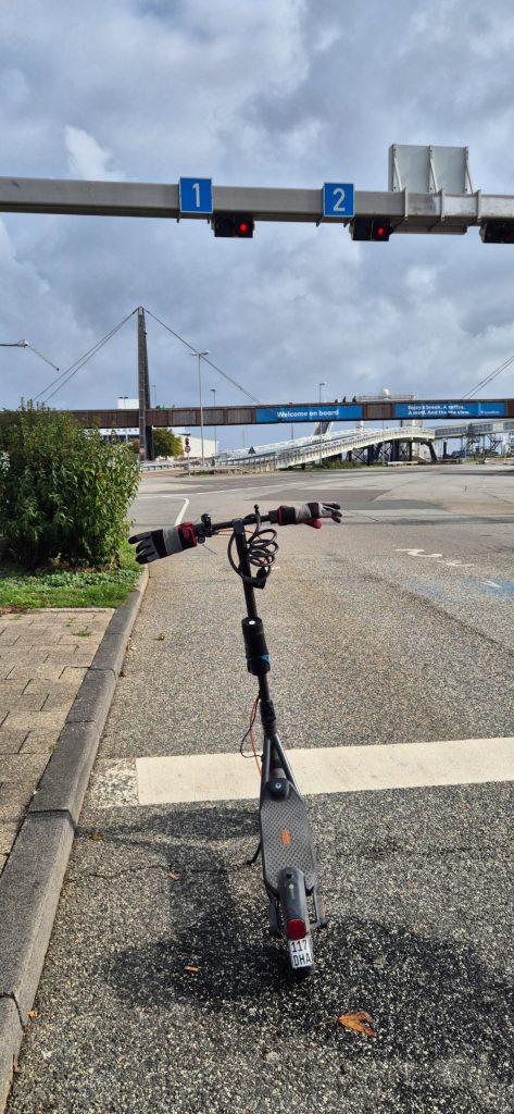 A Segway F2 Pro electric scooter parked on a road under traffic signals.