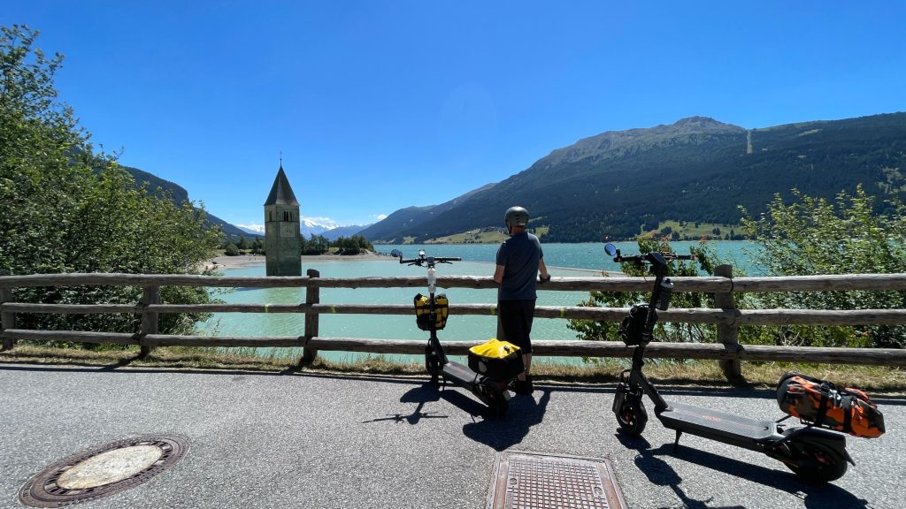 Segway MAX G3 electric scooters parked at a railing overlooking Lake Reschen