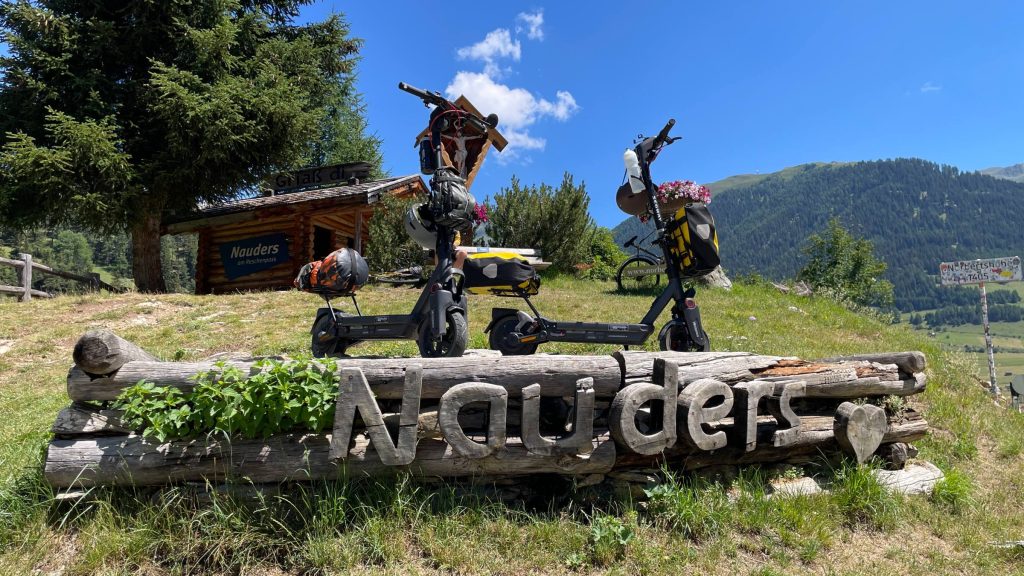 Two Segway MAX G3 electric scooters behind the Nauders sign near the Reschen Pass