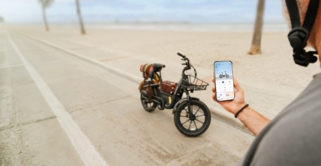 Rider holding a phone with the Segway Mobility app next to a parked Segway MUXI Pro