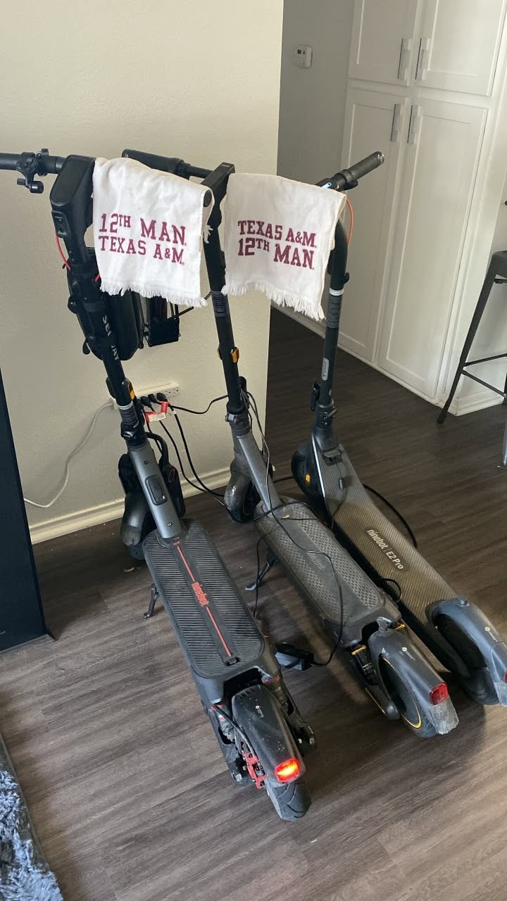 Three Segway electric scooters, including a MAX G3 Plus, parked together inside a college apartment.
