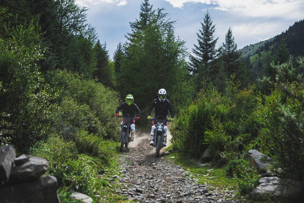Riders on Segway Xaber 300 electric dirt bikes on a narrow forest trail