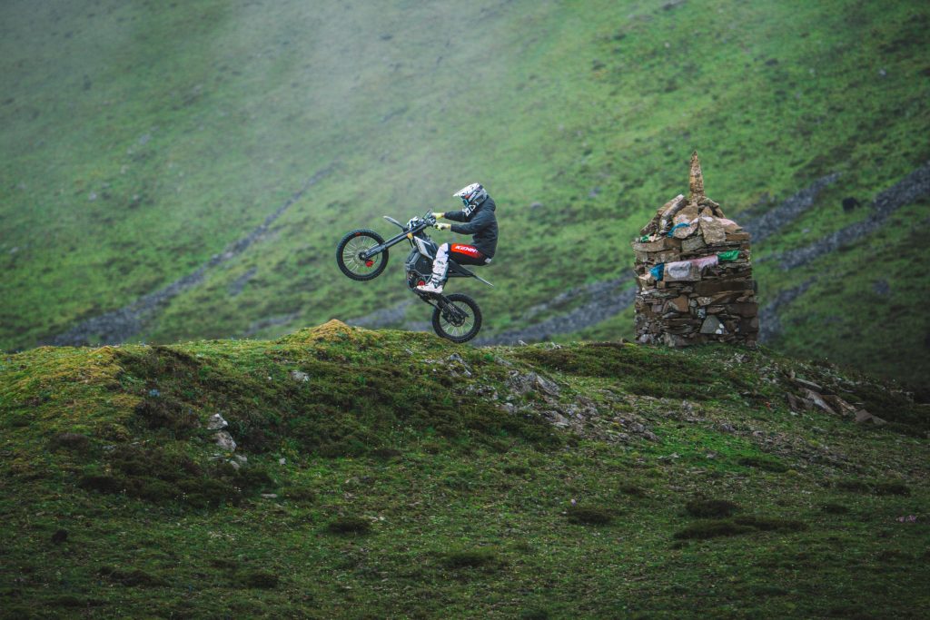 Riders on Segway Xaber 300 electric dirt bikes on a green hillside