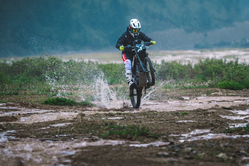 Rider crossing a shallow river on a Segway Xaber 300 electric dirt bike