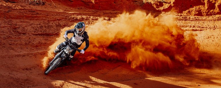 Rider kicking up red sand on a Segway Xaber 300 electric dirt bike in Utah