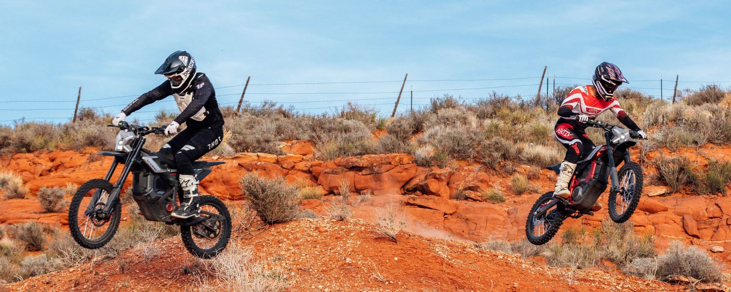Two riders on Segway Xaber 300 electric dirt bikes on red rock terrain in Utah