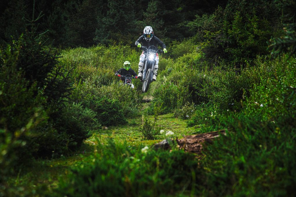 Rider on a Segway Xaber 300 electric dirt bike in a shaded woodland